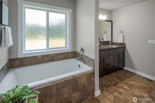 full bath featuring vanity, plenty of natural light, a garden tub, and visible vents