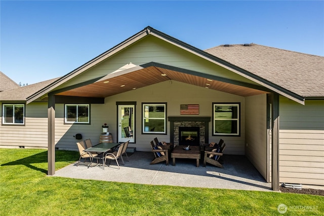 rear view of property featuring a shingled roof, a stone fireplace, crawl space, a patio area, and a yard