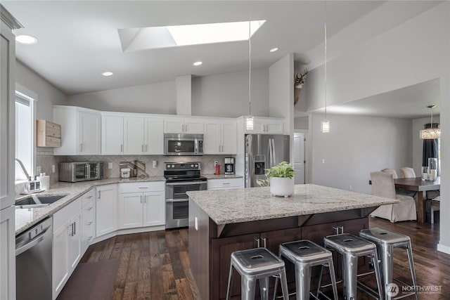 kitchen featuring backsplash, a kitchen bar, dark wood finished floors, a sink, and stainless steel appliances