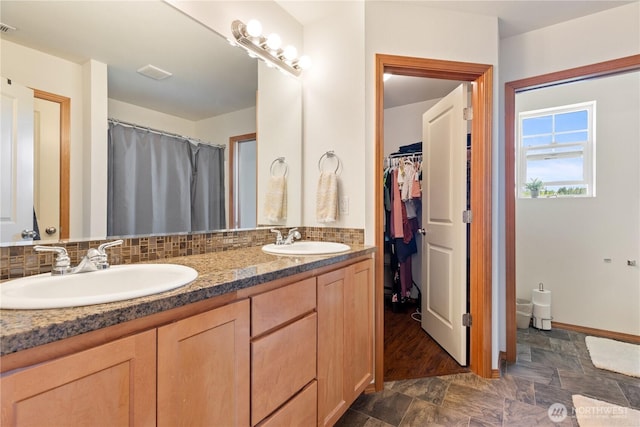 full bathroom featuring double vanity, a spacious closet, and baseboards