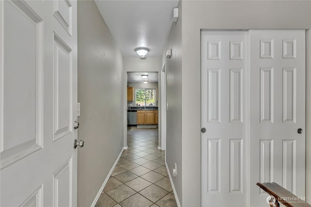 hallway featuring baseboards and light tile patterned floors