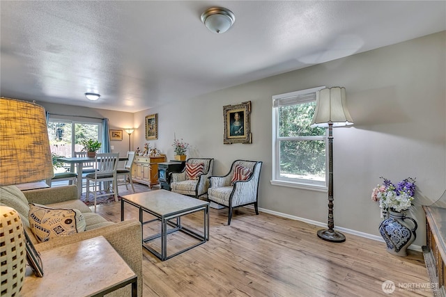 living room featuring baseboards, a textured ceiling, and light wood-style floors