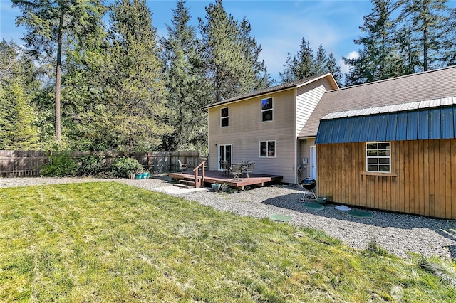 back of property with a lawn, a fenced backyard, a deck, and metal roof