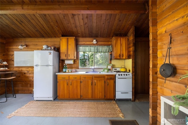 kitchen with a sink, wooden walls, white appliances, and light countertops