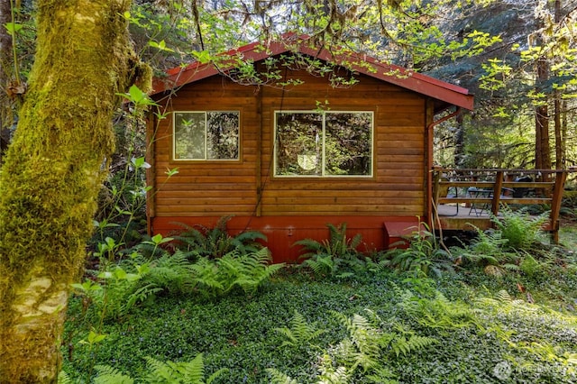 view of side of home featuring a wooden deck and log veneer siding