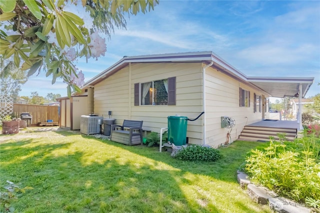 rear view of property featuring a yard, fence, and central AC