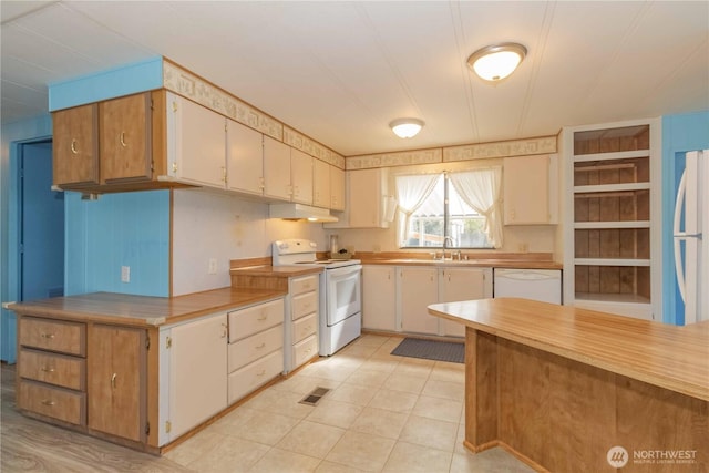 kitchen with under cabinet range hood, light tile patterned flooring, white appliances, and light countertops