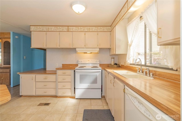 kitchen with under cabinet range hood, light tile patterned floors, white appliances, a sink, and light countertops