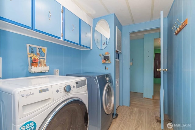 laundry area with washer and dryer, light wood-type flooring, and cabinet space