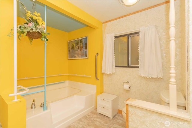 bathroom with crown molding, toilet, and a garden tub