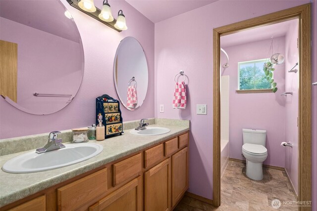full bath with double vanity, toilet, baseboards, and a sink