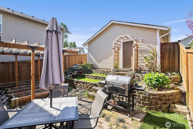 view of patio featuring area for grilling, a garden, outdoor dining area, and a fenced backyard