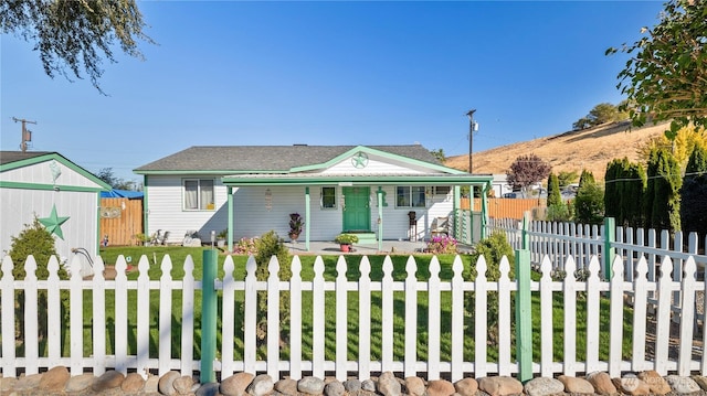 bungalow-style house with covered porch, a fenced front yard, and a front lawn