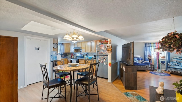 dining room with a textured ceiling, a notable chandelier, and light wood-style flooring