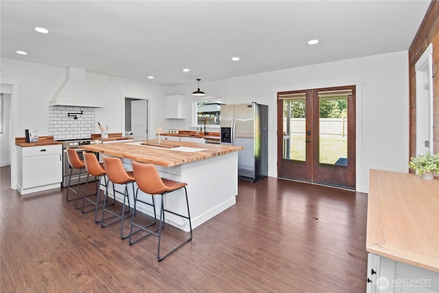 1517 Pioneer Hwy, Silvana, WA 98287 - kitchen with butcher block counters, french doors, dark wood-type flooring, custom range hood, and stainless steel appliances