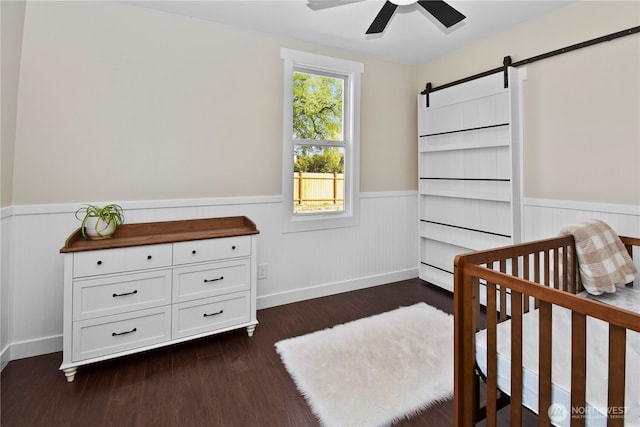 1517 Pioneer Hwy, Silvana, WA 98287 - bedroom featuring a barn door, wainscoting, a crib, and dark wood finished floors