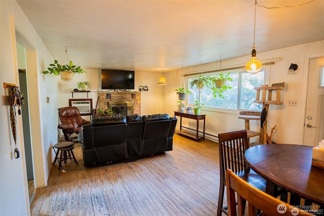 living room with a baseboard heating unit, wood finished floors, and a fireplace