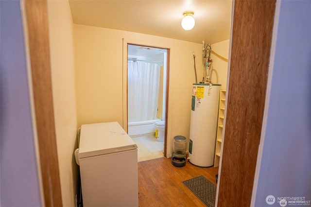 interior space with laundry area, water heater, and wood finished floors