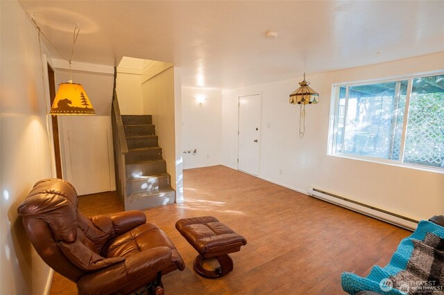 living room featuring baseboards, a baseboard radiator, wood finished floors, and stairway