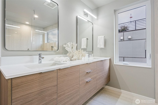 full bath with double vanity, baseboards, a sink, and a shower with shower door