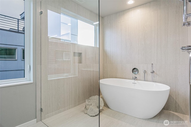 bathroom featuring a freestanding tub, walk in shower, and tile walls