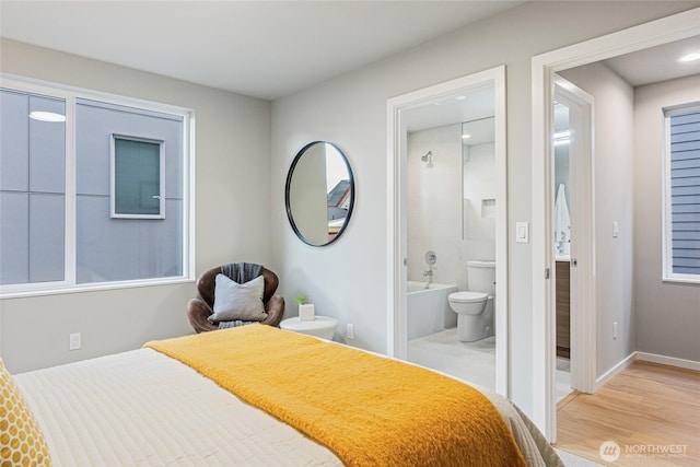bedroom featuring baseboards, ensuite bathroom, and wood finished floors
