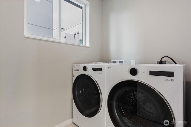 clothes washing area with washer and dryer, baseboards, and cabinet space