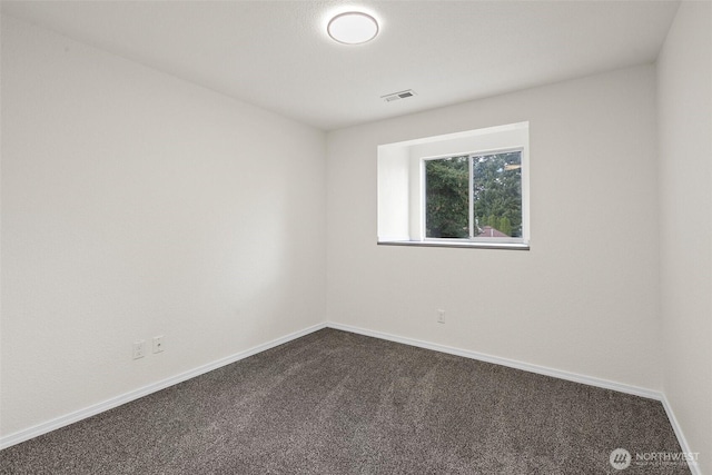 unfurnished room featuring baseboards, visible vents, and dark carpet
