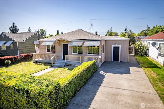 bungalow featuring a front yard, driveway, and roof with shingles