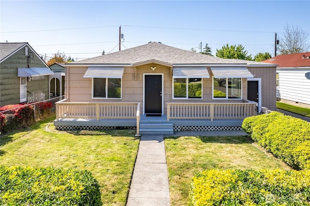 bungalow-style house featuring a shingled roof, a front lawn, and a wooden deck