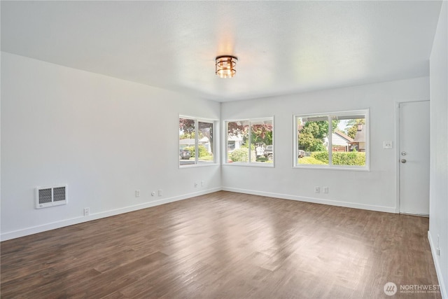unfurnished room with dark wood-style flooring, baseboards, and visible vents