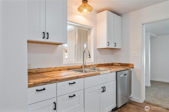 kitchen with stainless steel dishwasher, a sink, butcher block counters, and white cabinets