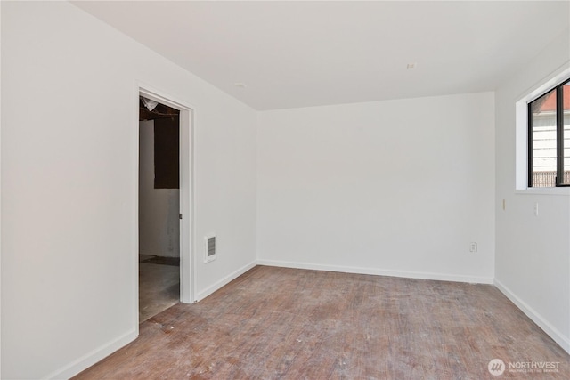 empty room featuring baseboards, visible vents, and wood finished floors