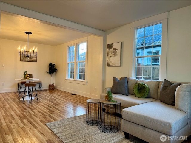 living room featuring baseboards, an inviting chandelier, and wood finished floors