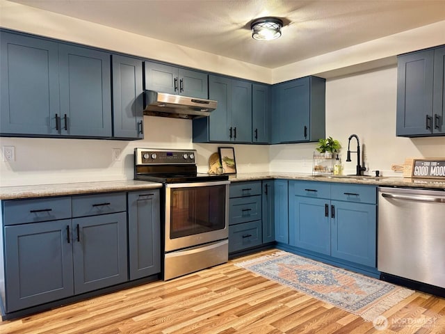 kitchen with appliances with stainless steel finishes, under cabinet range hood, and blue cabinets