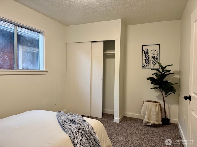 carpeted bedroom with a closet, a textured ceiling, and baseboards