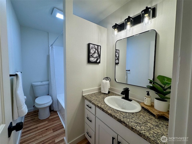 bathroom with wood finished floors, vanity, baseboards, toilet, and shower / bath combo with shower curtain