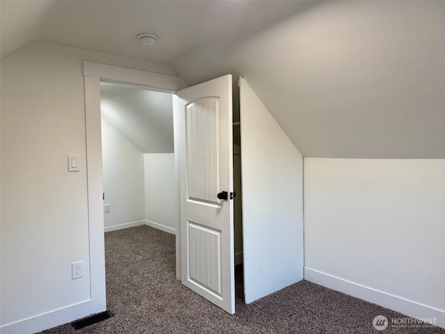bonus room with baseboards, dark colored carpet, and lofted ceiling