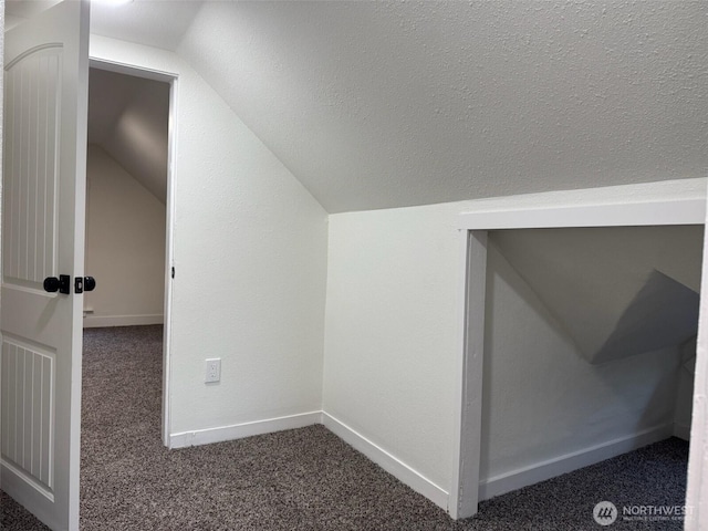 additional living space featuring baseboards, dark carpet, and lofted ceiling