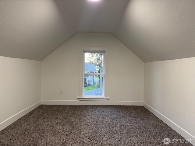 bonus room featuring baseboards, lofted ceiling, and dark colored carpet