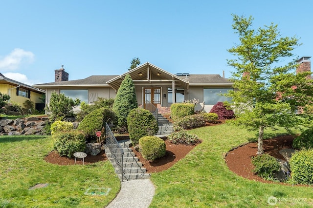view of front of home featuring french doors, stairs, a chimney, and a front lawn