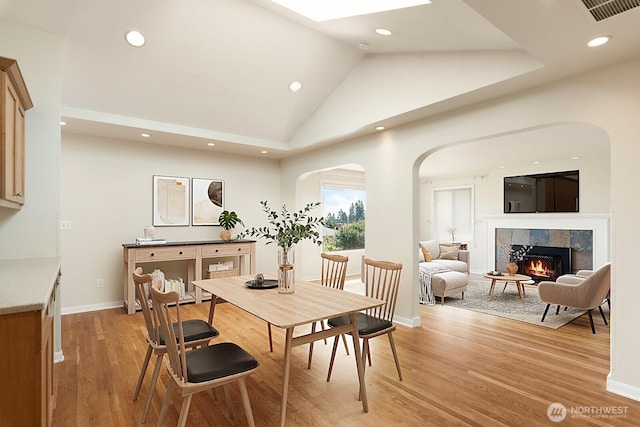 dining space with visible vents, a tiled fireplace, baseboards, light wood-style floors, and recessed lighting