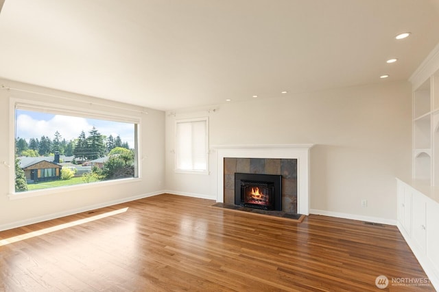 unfurnished living room with recessed lighting, baseboards, wood finished floors, and a tile fireplace