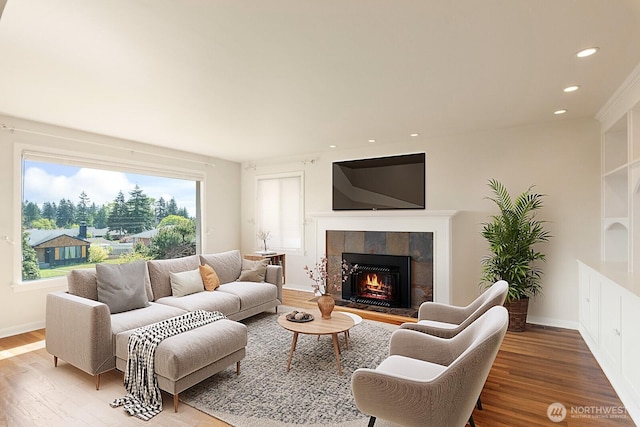 living area with baseboards, a fireplace, recessed lighting, and wood finished floors