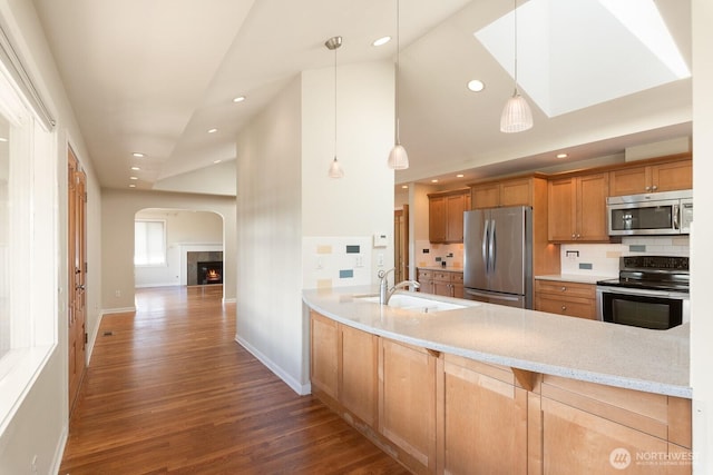 kitchen featuring arched walkways, appliances with stainless steel finishes, dark wood finished floors, and tasteful backsplash