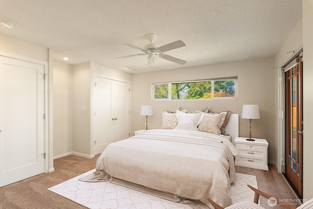 bedroom featuring light colored carpet, a textured ceiling, a ceiling fan, baseboards, and a closet