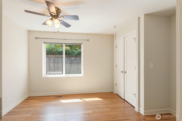 spare room featuring baseboards, a ceiling fan, light wood-type flooring, and visible vents
