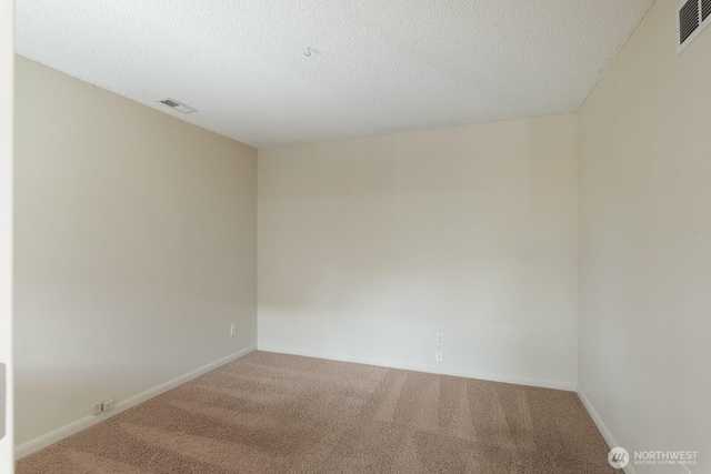 carpeted empty room with visible vents, a textured ceiling, and baseboards