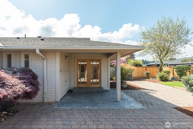 view of exterior entry with french doors, fence, and a patio