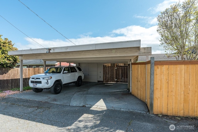 view of parking with a garage, fence, and a carport